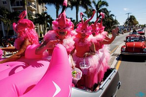 A pink-themed parade float with people in matching costumes. - Villa Del Mar Gulf View Condo On Gorgeous Mid Island Beach, Heated Pool, Elevator (Fort Myers Beach)