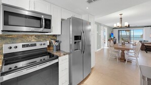 Una cocina moderna con electrodomésticos de acero inoxidable, encimera de granito y un comedor con vistas.