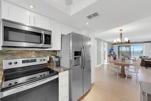 A modern kitchen with stainless steel appliances, a granite countertop, and a dining area with a view.