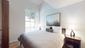 A bedroom with a large bed, a window with a view, a painting on the wall, and a nightstand with a lamp. - 1BR + Loft | Glacier Lodge | King Bed | Near Gondola | Private Balcony | Free Ski Valet (Whistler)