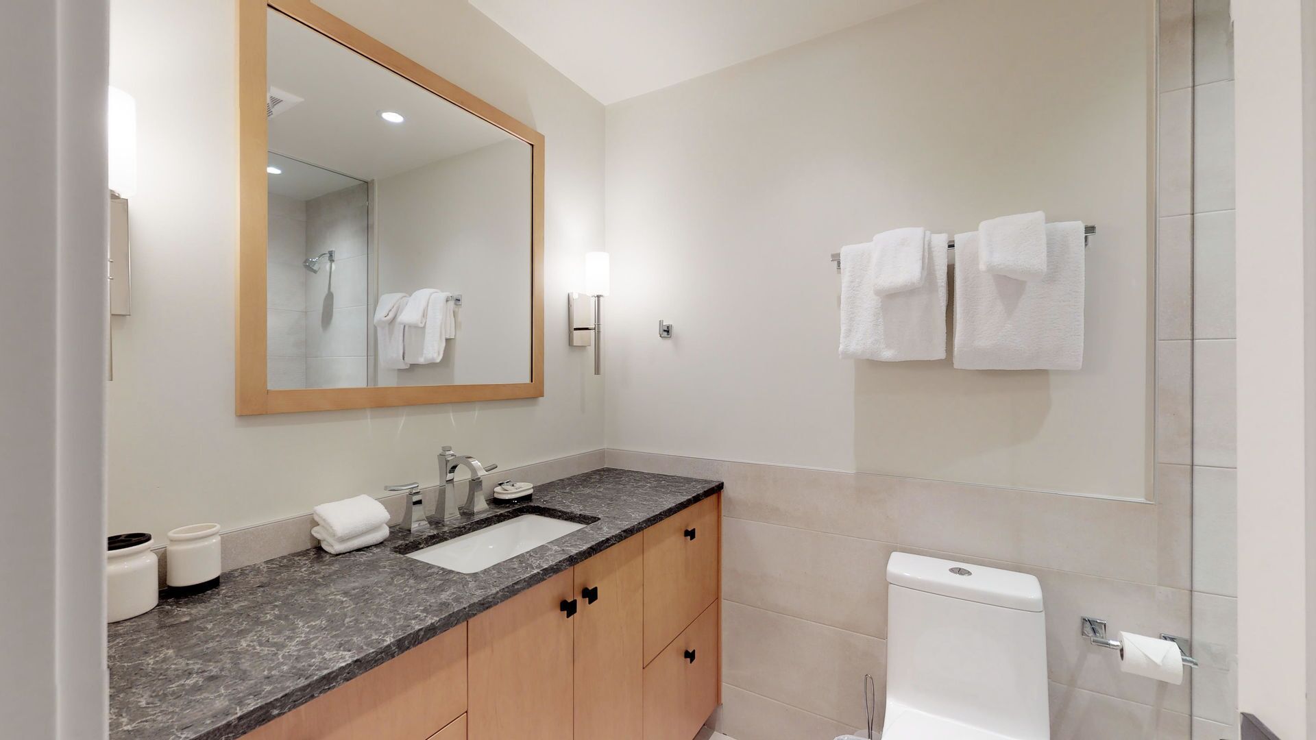 Une salle de bain moderne avec un lavabo, un miroir et des toilettes.