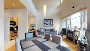 A modern living room with a fireplace, a dining area, and a kitchen. - 1BR + Loft | Glacier Lodge | King Bed | Near Gondola | Private Balcony | Free Ski Valet (Whistler)