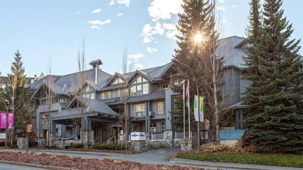 A multi-story building with a traditional architectural style, featuring large windows and a stone facade. - 1BR + Loft | Glacier Lodge | King Bed | Near Gondola | Private Balcony | Free Ski Valet (Whistler)