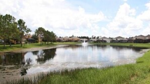 A calm water feature with a bridge, surrounded by greenery and residential buildings. - Perfect vacation Gated Resort with Private Pool (Kissimmee)