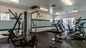 A gym with various exercise equipment including treadmills, ellipticals, and weight machines.