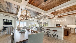 Une cuisine spacieuse dotée d’un grand îlot central, d’un plafond en bois et de luminaires modernes.