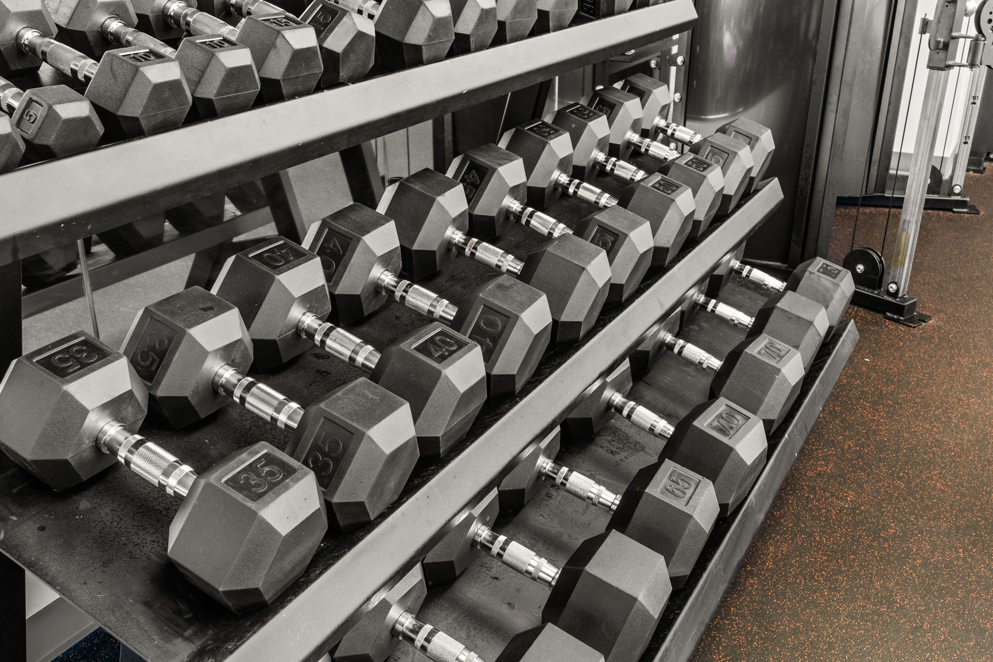 A rack of hexagonal dumbbells with visible weight markings.