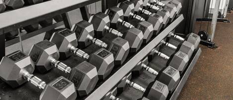 A rack of hexagonal dumbbells with visible weight markings.