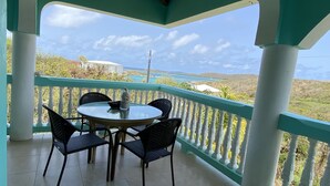 A covered outdoor seating area with a table and chairs, overlooking a scenic landscape.