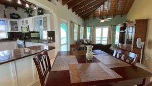 A spacious kitchen with white cabinets, a black countertop, and a dining area with a wooden table and chairs.