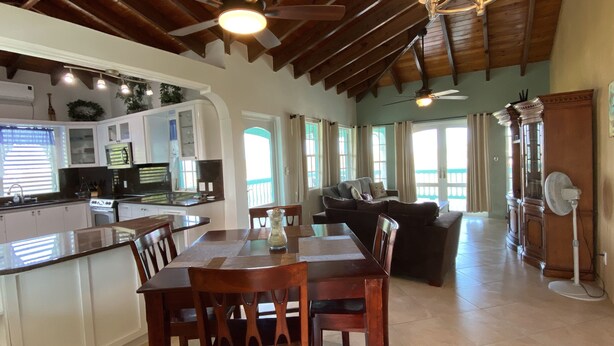 A spacious kitchen with a dining area, wooden ceiling beams, and a large window.