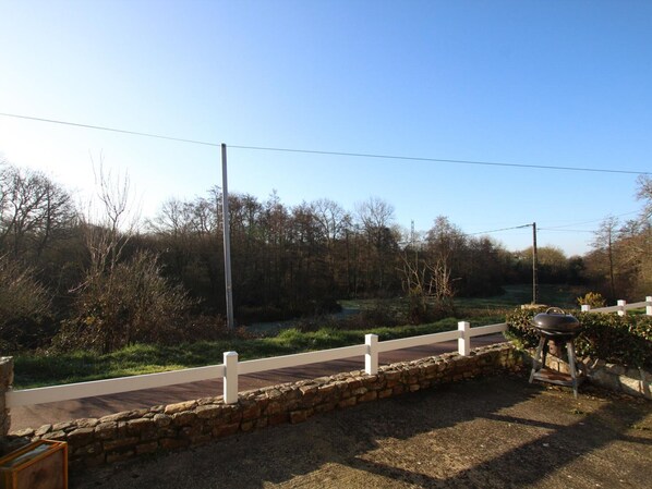 A rural setting with a paved path, stone wall, and a barbecue grill. - Comfortable semi-detached house between sea and countryside (Lessay)