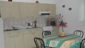 Une cuisine compacte avec un coin repas. Elle comprend un évier, un four à micro-ondes, une cuisinière et une table à manger avec des chaises.