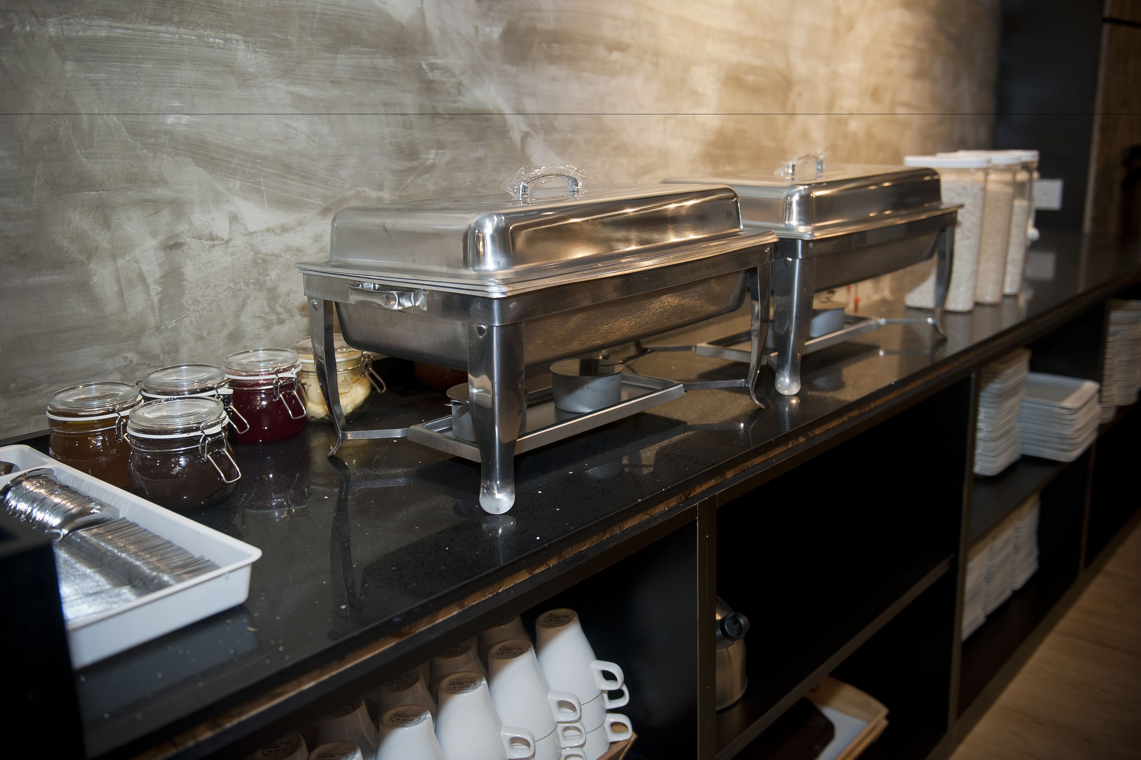 Un'impostazione buffet con piatti da portata in acciaio inossidabile, distributori di condimenti e diversi contenitori per alimenti.