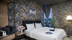 Une chambre d’hôtel bien rangée, avec un lit, une table de chevet dotée d’une lampe, un bureau avec des sacs, et un mur orné d’un motif décoratif.
