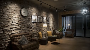 Un salon chaleureux avec un mur en pierre, un canapé en cuir et une table basse.