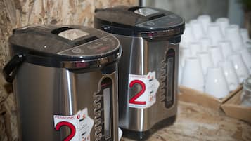 Two stainless steel dispensers labeled 'Pensonic' with a capacity of 5 oz. They are placed on a wooden surface with a keyboard and white cups in the background.