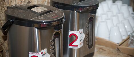 Two stainless steel dispensers labeled 'Pensonic' with a capacity of 5 oz. They are placed on a wooden surface with a keyboard and white cups in the background.