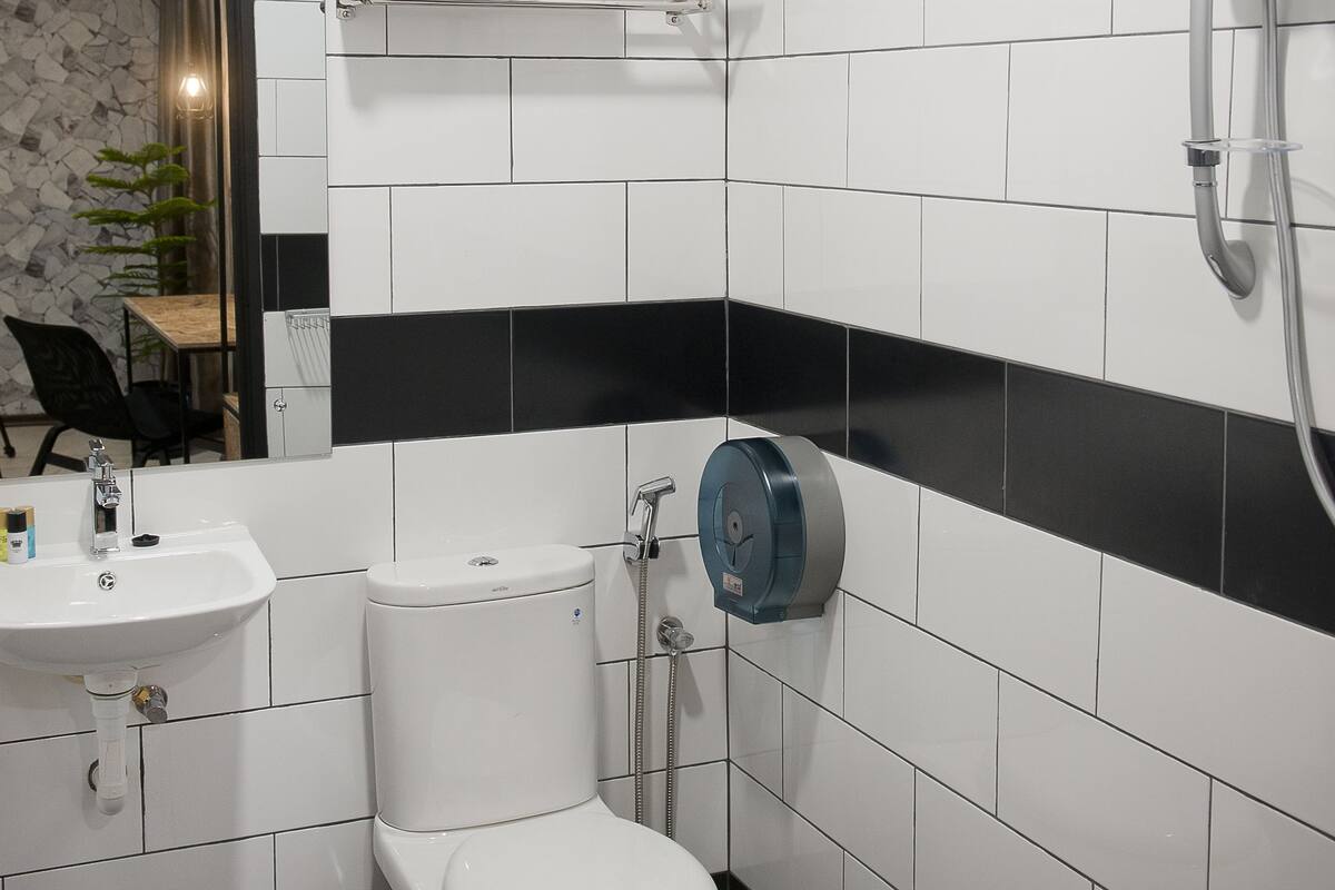 A modern bathroom with white and black tiles, a toilet, a sink, and a shower.