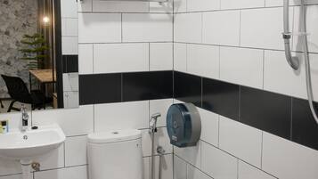 A modern bathroom with white and black tiles, a toilet, a sink, and a shower.
