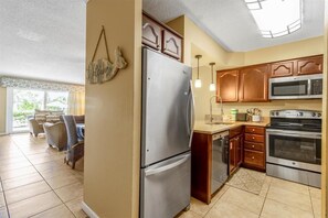 Fully equipped kitchen with a refrigerator, microwave, and oven, plus a sink and wooden cabinets.