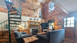 A cozy cabin interior with a wooden interior, a fireplace, a television, and a spiral staircase. - ER13 - Moose Manor  Great location - Close to town! (Pigeon Forge)