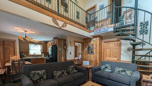 A spacious living area with two sofas, a wooden coffee table, and a spiral staircase. - ER13 - Moose Manor  Great location - Close to town! (Pigeon Forge)