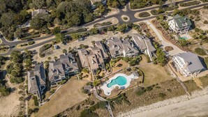 An aerial view of a coastal residential area with multiple houses, a swimming pool, and a beach. - Happy Days Luxury Oceanfront Beach Villa in DeBordieu (Georgetown)