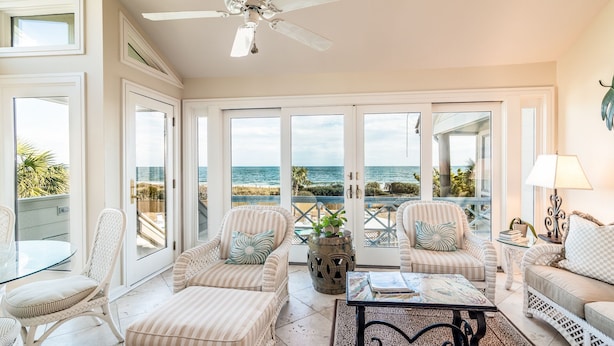 A spacious balcony with a view of the ocean, wicker furniture, and a ceiling fan. - Happy Days Luxury Oceanfront Beach Villa in DeBordieu (Georgetown)