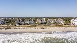 A beachfront property with multiple houses, a sandy beach, and waves crashing onto the shore. - Happy Days Luxury Oceanfront Beach Villa in DeBordieu (Georgetown)