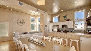 A spacious kitchen with wooden walls, white cabinets, and a central island with chairs. - Gulf views from rooftop deck, 2 heated community pools, gated community! (Port Aransas)