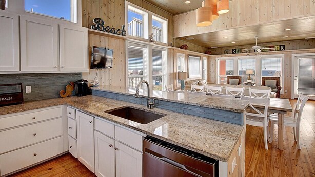 A modern kitchen with white cabinets, a granite countertop, and a built-in dishwasher. - Gulf views from rooftop deck, 2 heated community pools, gated community! (Port Aransas)