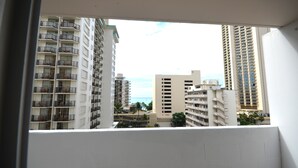 Vista de prédios altos com varandas, céu claro e uma vista distante do oceano.