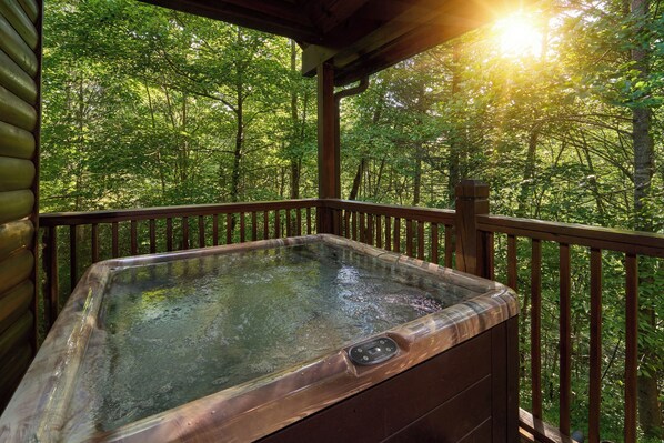 Un jacuzzi en una terraza de madera con vista al bosque.