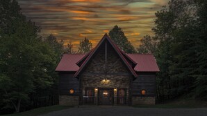 A log cabin with a stone facade, a red roof, and a front porch. - Family Fun | Theater, Gameroom, Hot Tub (Gatlinburg)