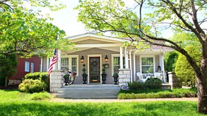A two-story house with a front porch, a flag, and a bicycle.