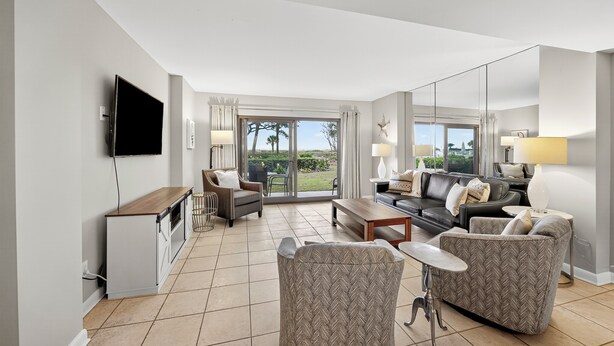 A modern living room with a flat-screen TV, a dining area, and a sofa set.