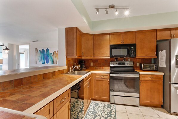 Una cocina moderna con armarios de madera, electrodomésticos de acero inoxidable y una isla grande con fregadero.