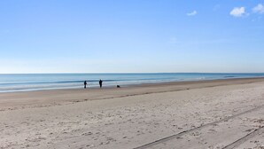 A wide sandy beach with a clear sky and calm sea.