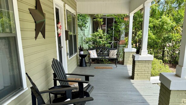 A covered porch with two black Adirondack chairs, a bench, and a small table with potted plants. - 2BR PERFECT location! Walk to Beach & Island View Casino! Casa Verde (Gulfport)