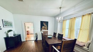A dining area with a wooden table and chairs, a chandelier, and a window with chevron-patterned curtains. - 2BR PERFECT location! Walk to Beach & Island View Casino! Casa Verde (Gulfport)