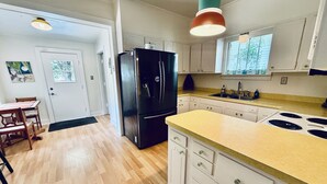 A kitchen with wooden flooring, white cabinets, a black refrigerator, a yellow countertop, and a window with a view of trees. - 2BR PERFECT location! Walk to Beach & Island View Casino! Casa Verde (Gulfport)
