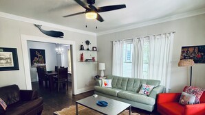 A living room with a ceiling fan, a dining area with a chandelier, and a red armchair. - 2BR PERFECT location! Walk to Beach & Island View Casino! Casa Verde (Gulfport)