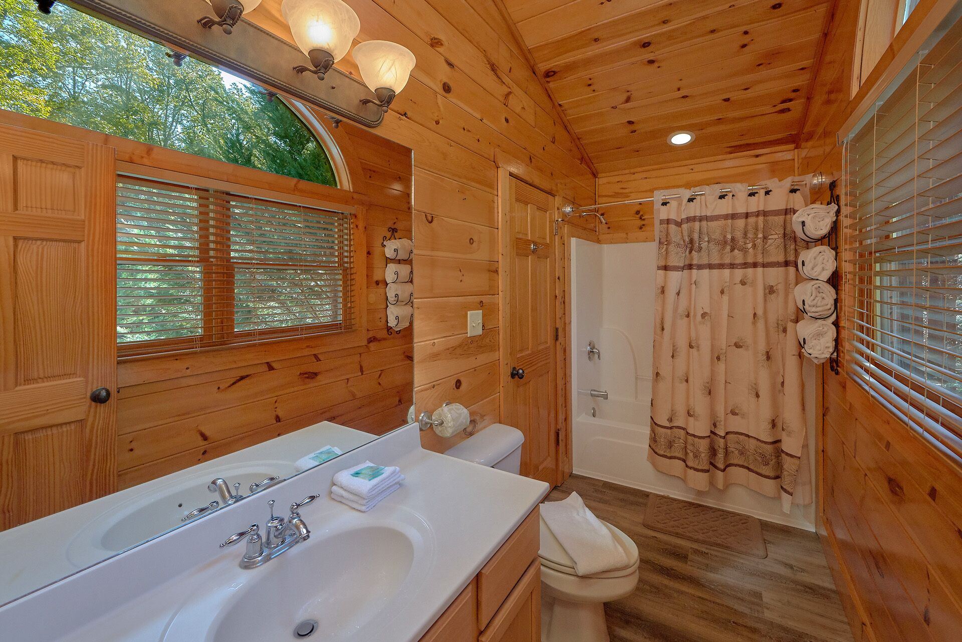 Ein Badezimmer einer Holzhütte mit einem großen Waschbecken, einer Toilette und einer Dusche.