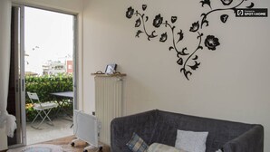 Ett vardagsrum med en grå soffa, ett element och en väggdekoration i form av blommor.