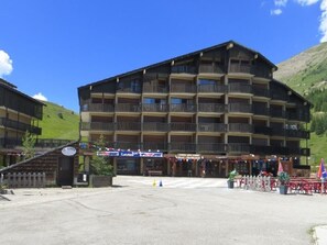 Guests can enjoy scenic views from the balconies of this traditional chalet-style building, which features a seating area with tables and chairs.