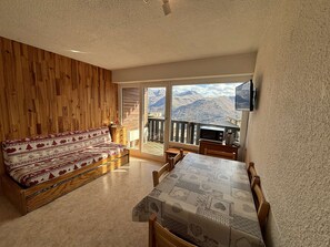 Enjoy a scenic mountain view from the large window in this inviting room, featuring a sofa and dining area.
