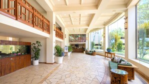 A spacious lobby with a large aquarium, potted plants, a reception desk, and a seating area with a view of the outdoors.