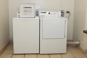 Uma área de lavanderia com duas máquinas de lavar e secar empilhadas, um painel de controle e um sistema de ventilação.