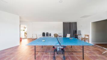 Una habitación amplia con mesa de ping pong, dos altavoces y extintor.